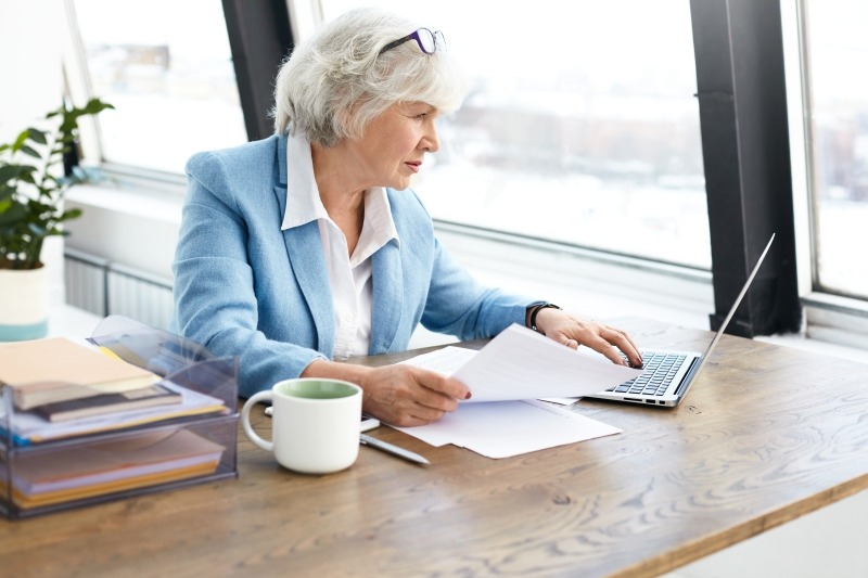 Eine ältere Dame sitzt im Büro und arbeitet am Computer